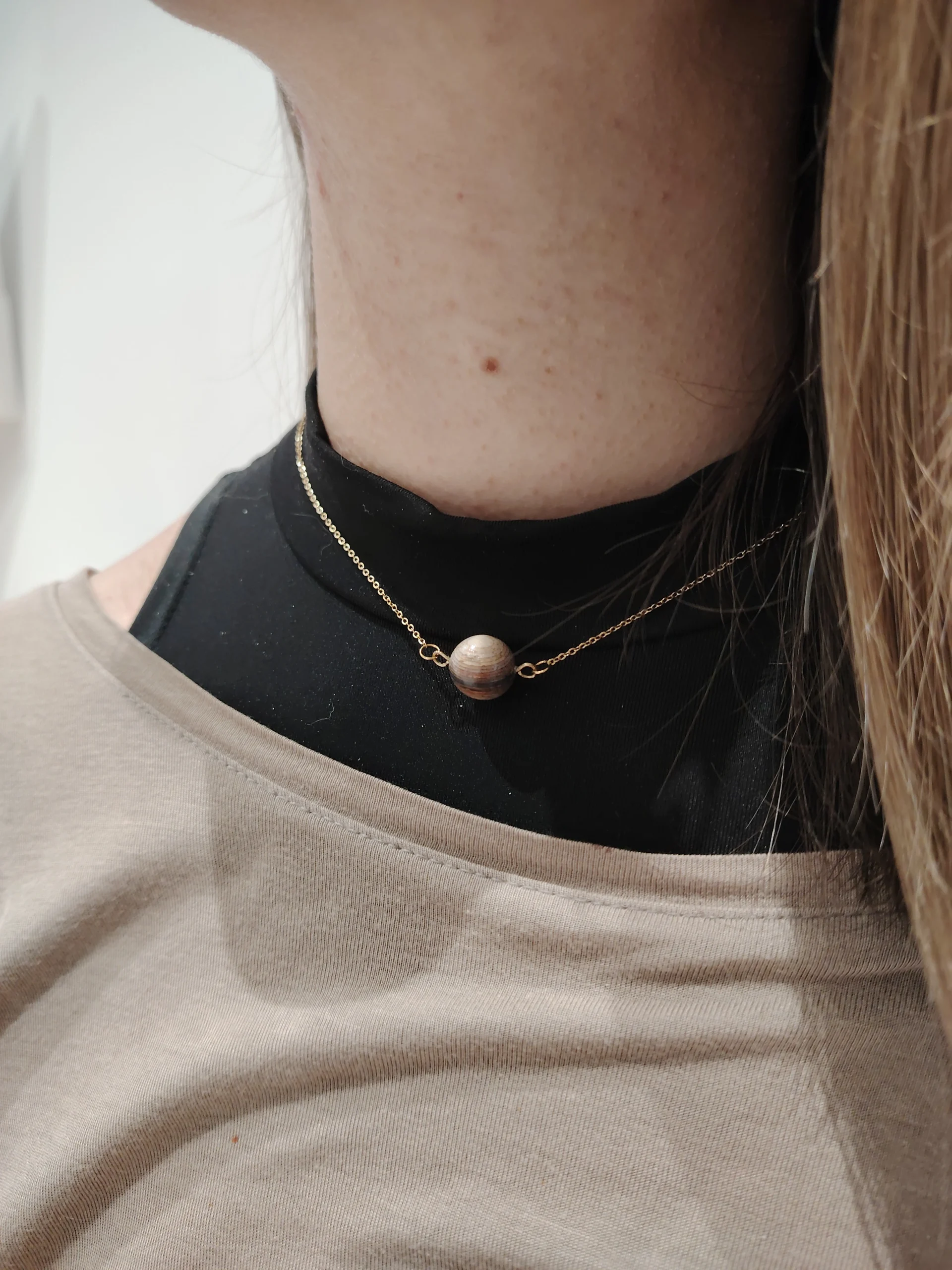 personne portant un collier en forme de sphère fait avec un dégrader de placage (du foncé au claire)