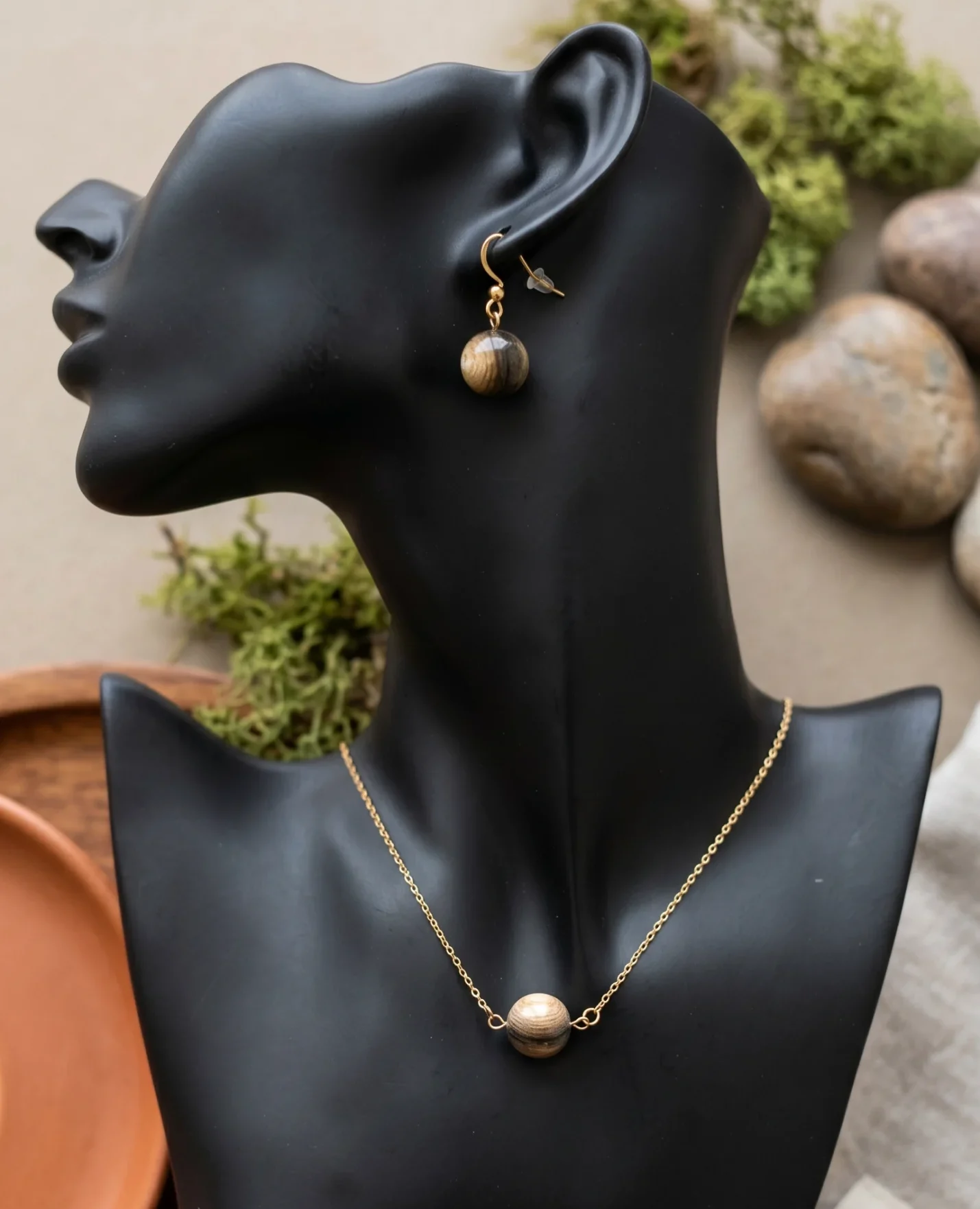 un buste noir avec un collier et une boucle d'oreille